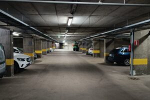 Iso helsinkiläinen pysäköintihalli, jossa on juuri rakannettu sähköautojen latausinfra. Kuvassa näkyy kattoon kiinnitettyjä kaapelihyllyjä ja kaapelointeja